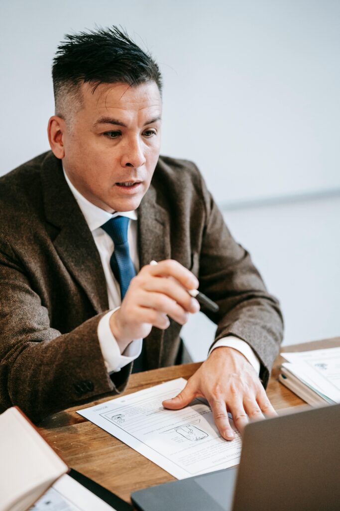 Focused professional man in suit engaging in a virtual meeting at office desk with documents.
